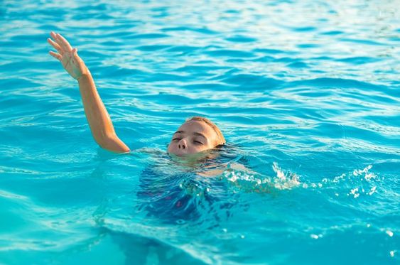 Child in pool, playful pose misread as distress