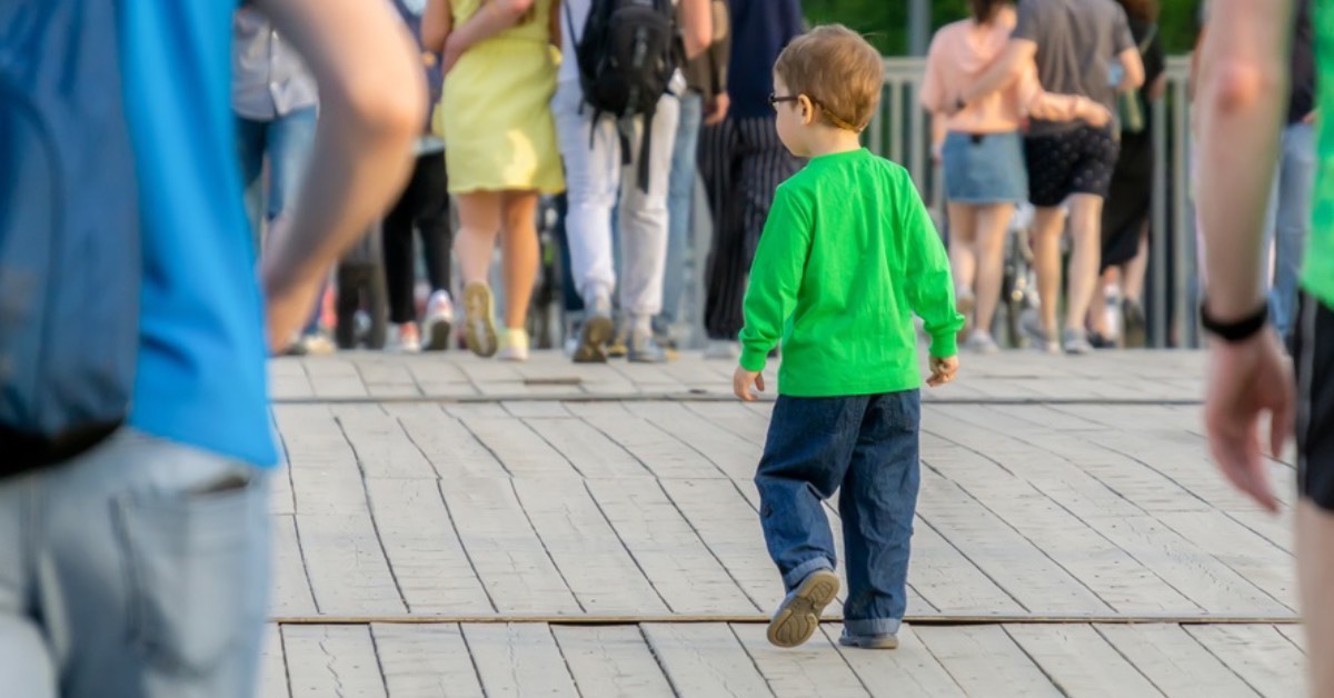 A child in a crowd with nearby parents observing